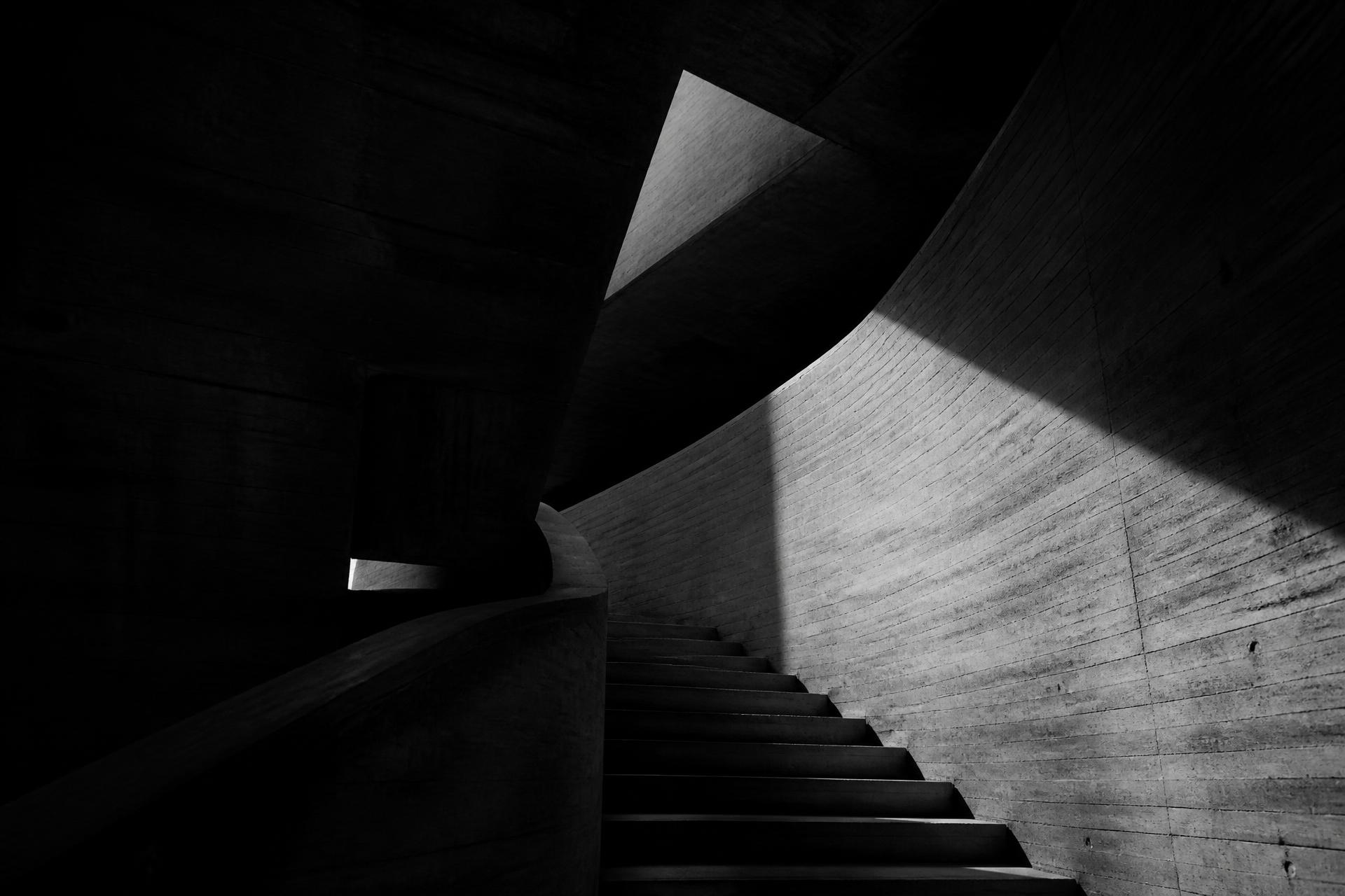 Curved concrete staircase in dramatic light and shadow